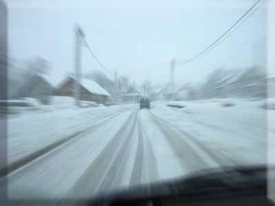 car on an empty snow covered road in winter conditions